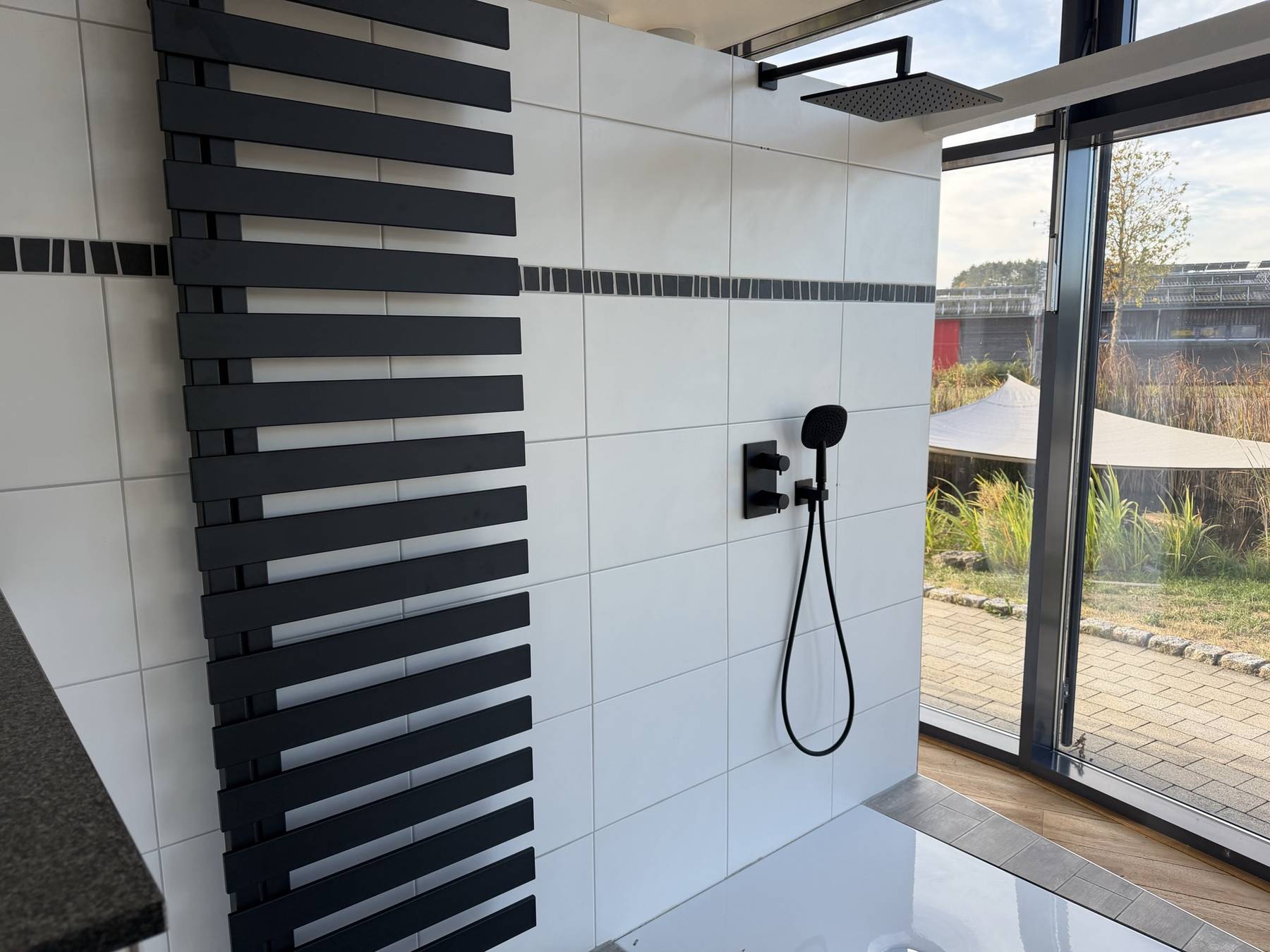 Dusche mit schwarzer Armatur und Designheizkörper
