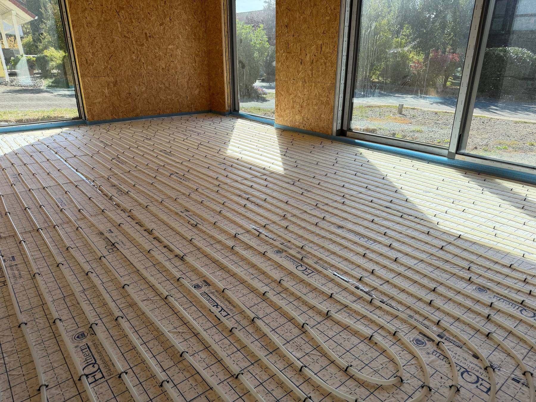 Verlegte Fußbodenheizung auf Trägerplatten in einem Neubau mit Fensterfront